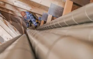 guy in attic installing hvac ducting