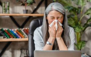 woman sneezing at desk